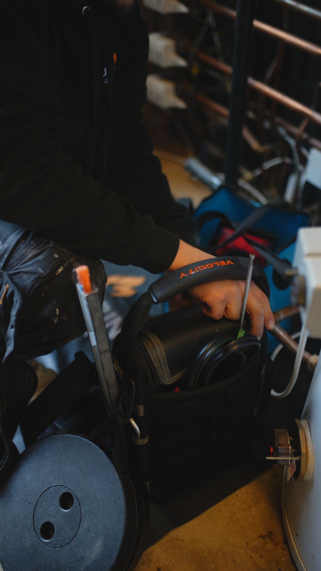 Plumbing on demand on a job with someone's hand over a tool bag